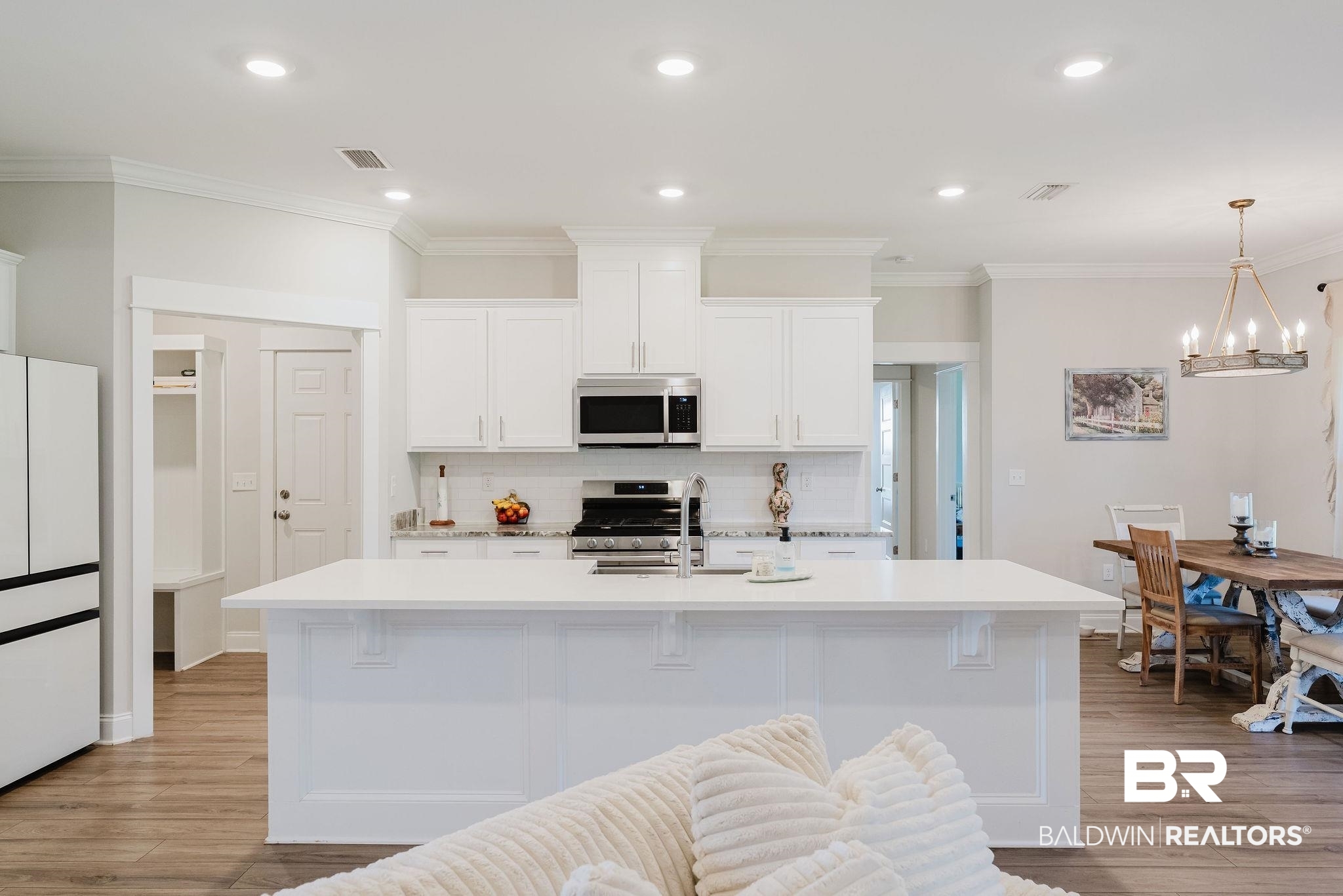 7872 Calverton Street Foley, AL 36535 - Photo 35 of 76 Bright kitchen featuring white cabinetry, a large center island with a sink, stainless steel appliances, and wood-finish flooring