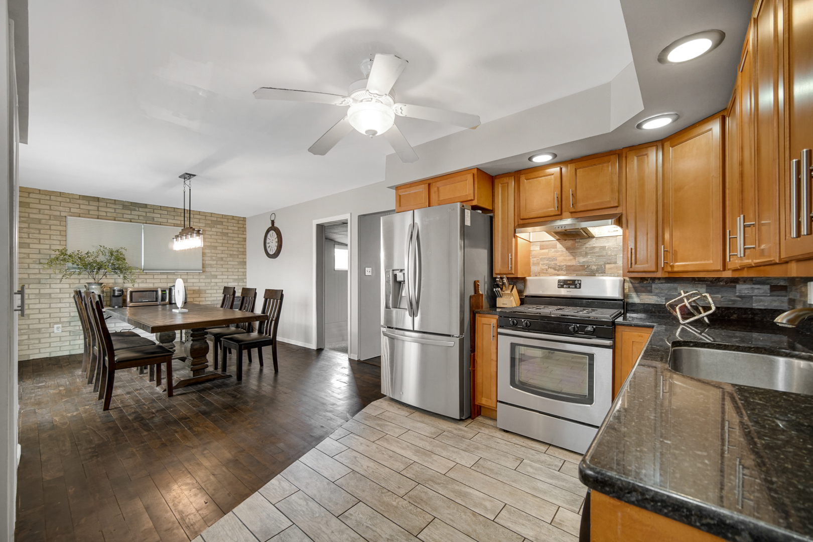 17509 Maple Avenue Lansing, IL 60438 - Photo 2 of 27 a kitchen with stainless steel appliances granite countertop a stove top oven a refrigerator a dining table and chairs with wooden floor