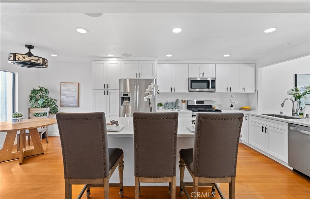 7 Boone Irvine, CA 92620 - Photo 13 of 38 a kitchen with stainless steel appliances granite countertop a dining table chairs refrigerator and sink