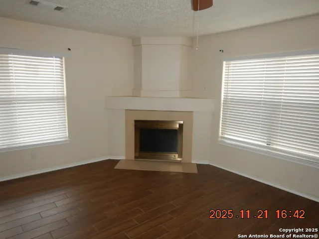 an empty room with wooden floor a fireplace and windows