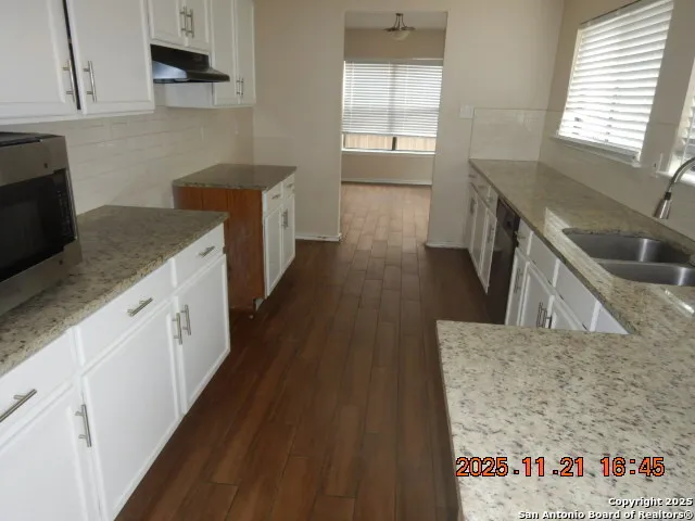 a kitchen with granite countertop a sink stove and cabinets