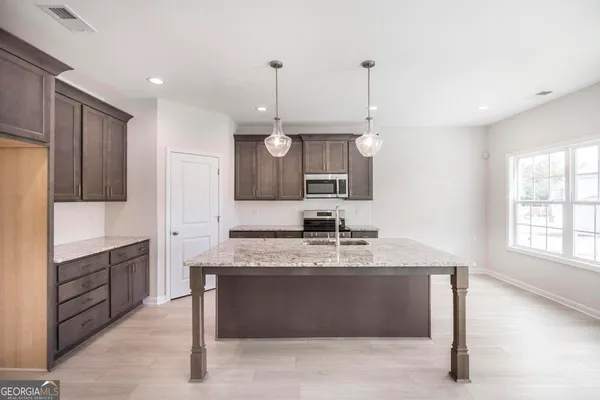 a large kitchen with granite countertop a sink stainless steel appliances and cabinets