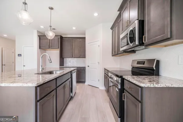 a kitchen with stainless steel appliances granite countertop a sink stove and refrigerator