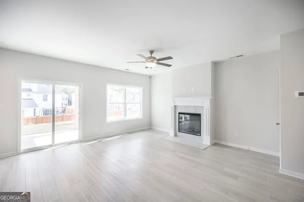an empty room with windows a fireplace and wooden floor