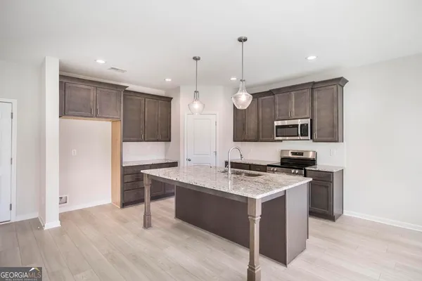 a kitchen with a stove a sink a refrigerator and a microwave