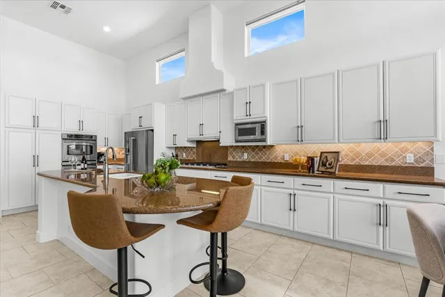 a kitchen with stainless steel appliances granite countertop a stove a sink a dining table and chairs