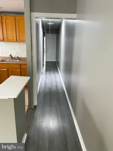 a view of a hallway with wooden floor and a kitchen
