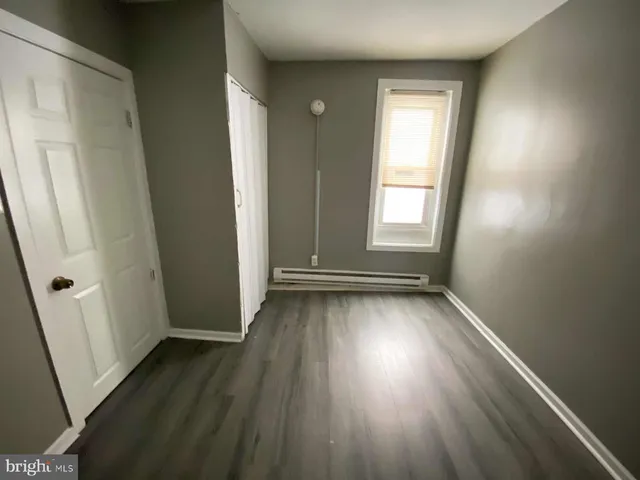 an empty room with wooden floor and window