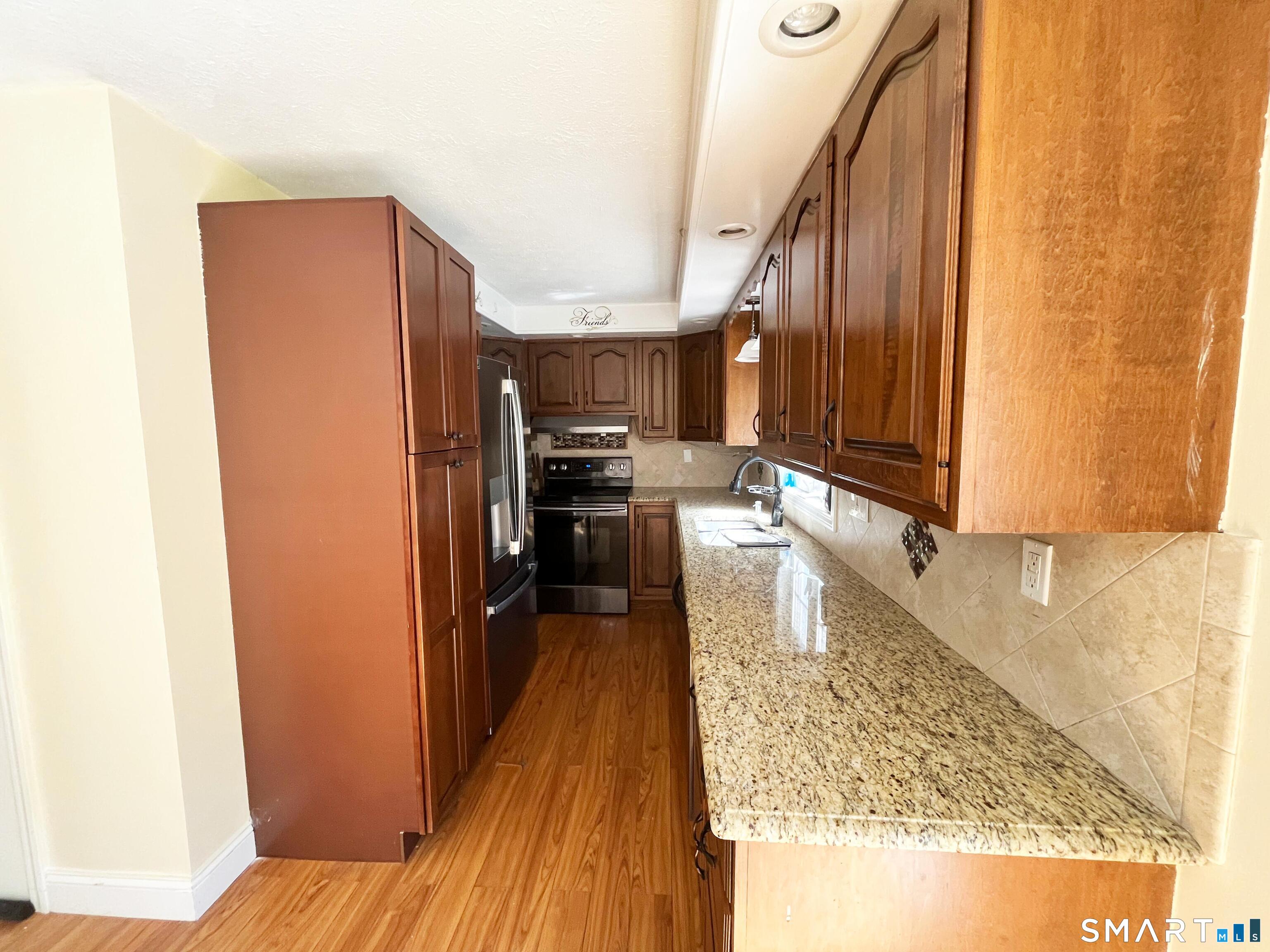 52 Monce Road Burlington, CT 06013 - Photo 20 of 26 a kitchen with kitchen island granite countertop wooden cabinets a refrigerator and a sink