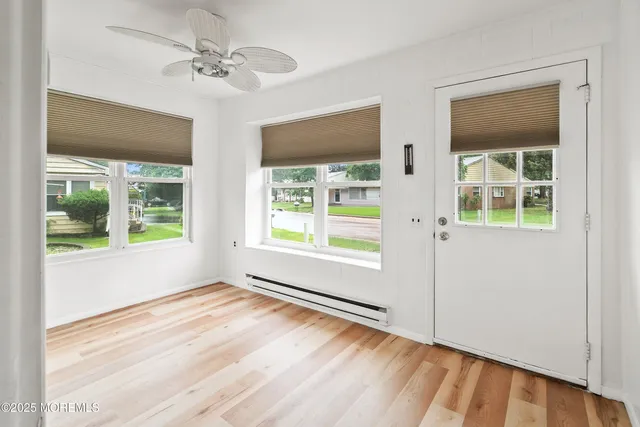 a view of empty room with wooden floor and fan