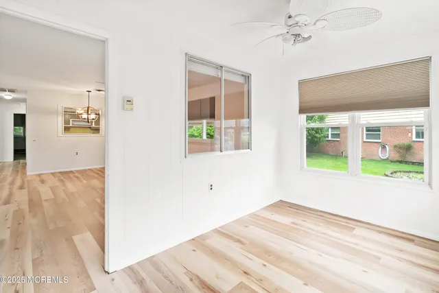 an empty room with wooden floor a ceiling fan and windows