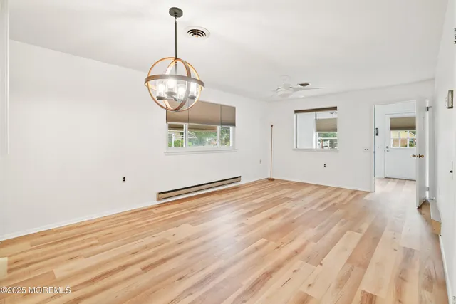 an empty room with wooden floor and ceiling fan