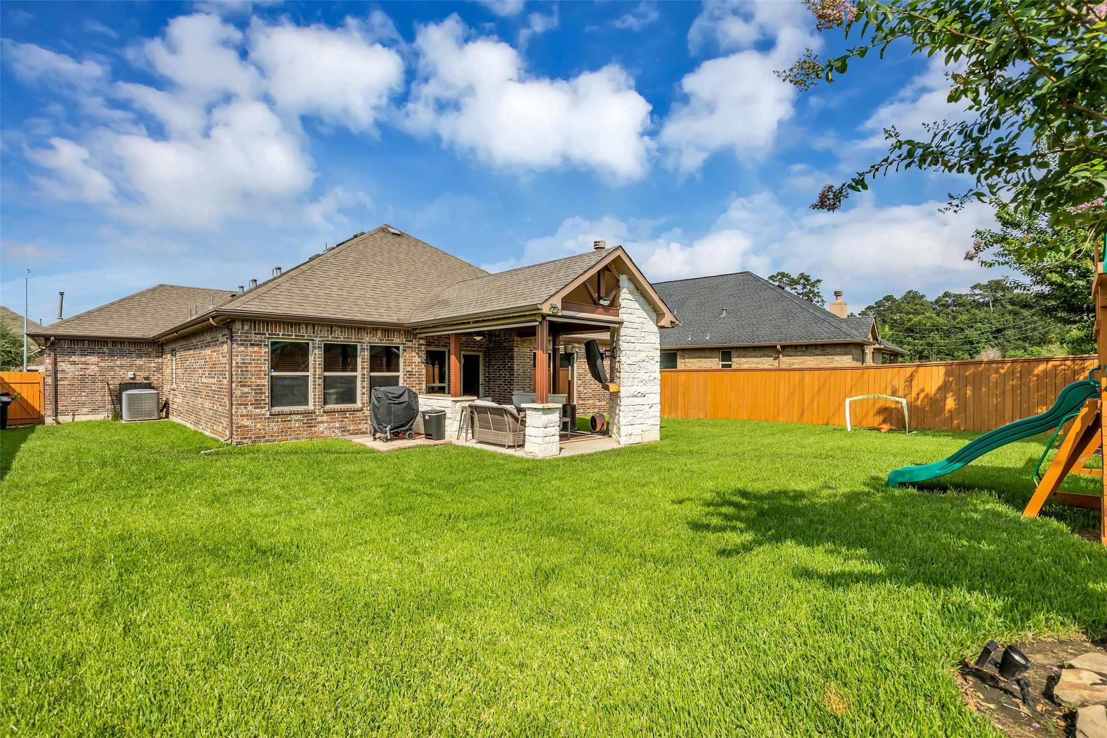 22907 Banff Brook Way Tomball, TX 77375 - Photo 22 of 26 An additional back view of the home highlights the covered patio, offering a shaded outdoor area that extends the living space into the backyard.
