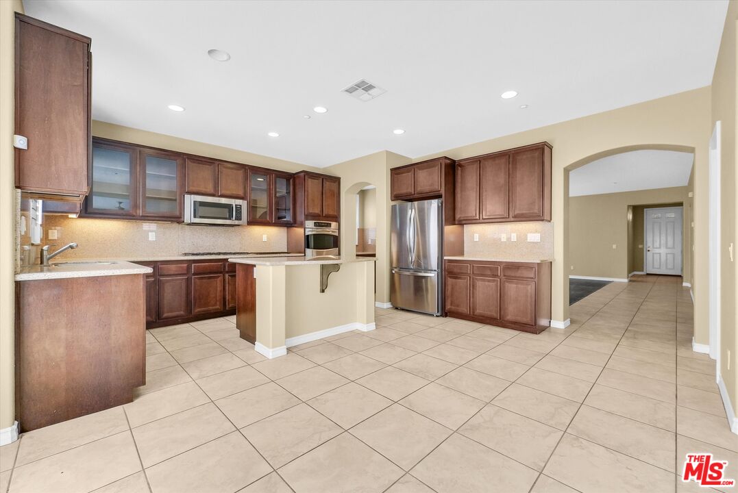 5611 Scharf Avenue Fontana, CA 92336 - Photo 12 of 49 a kitchen with granite countertop a refrigerator and cabinets