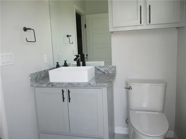 a bathroom with a granite countertop toilet sink and mirror
