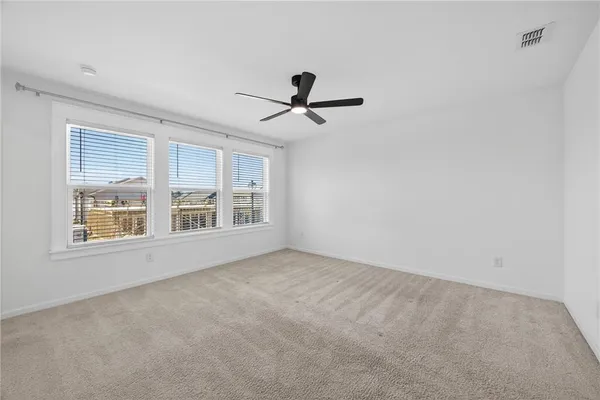 an empty room with chandelier fan and windows