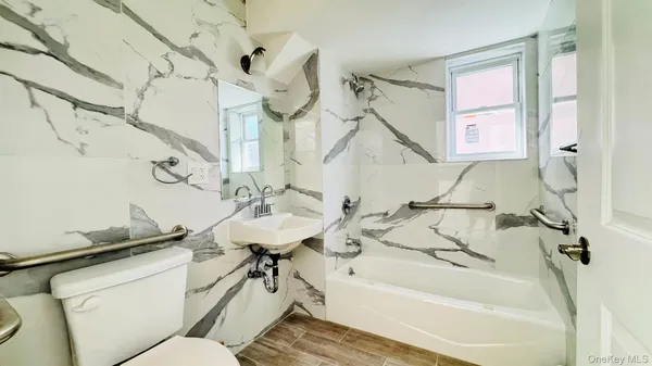 a bathroom with a sink and mirror with bathtub