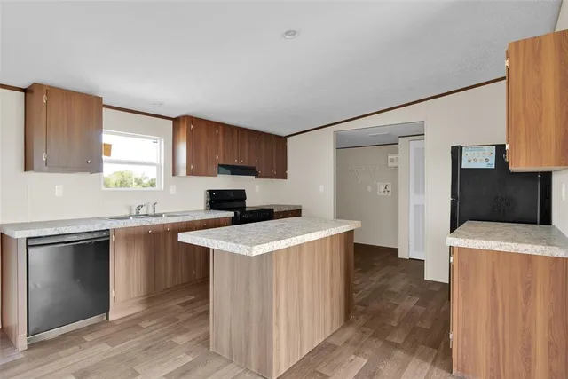 a kitchen with a stove top oven a sink a refrigerator and a window