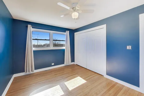 a view of empty room with wooden floor and fan