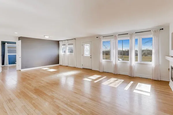 a view of an empty room with window and wooden floor