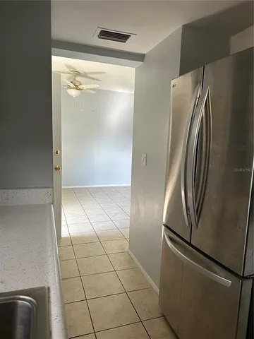 a view of a refrigerator in kitchen and an empty room