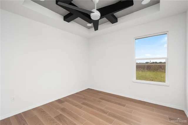 an empty room with a ceiling fan and wooden floor