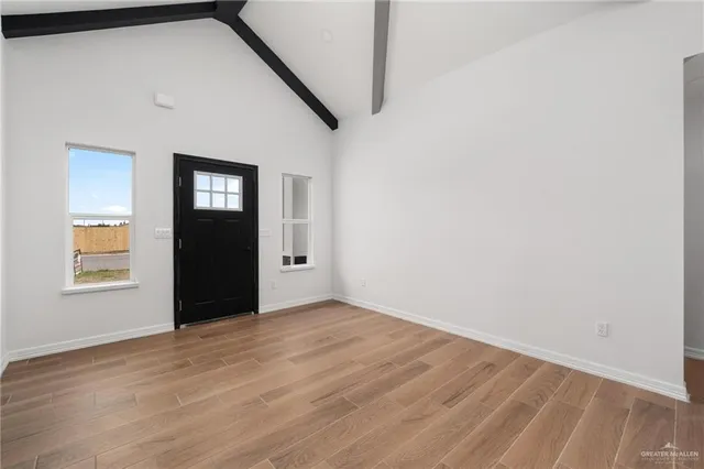a view of an empty room with wooden floor and a window