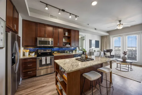 a kitchen with granite countertop a stove top oven a sink dishwasher a dining table and chairs with wooden floor