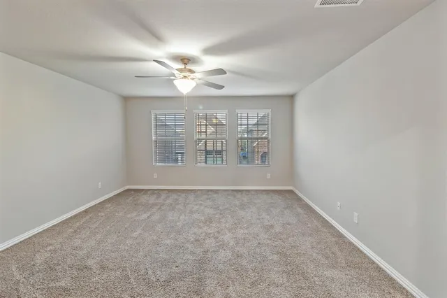 an empty room with chandelier fan and windows