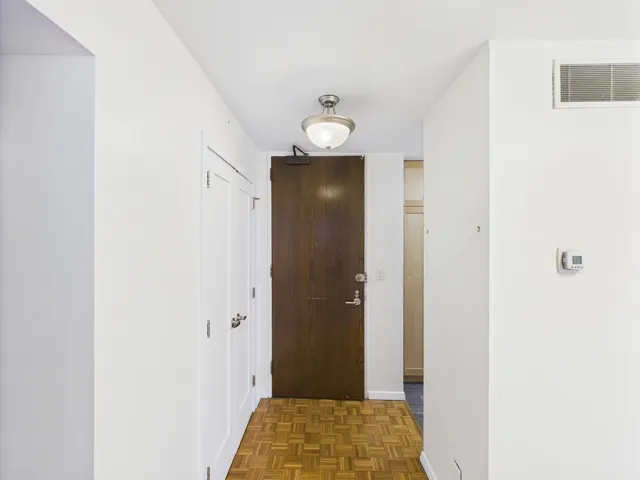 a view of a hallway with wooden floor and closet