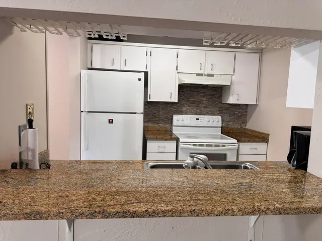 a view of kitchen with stainless steel appliances granite countertop a refrigerator stove oven and a sink