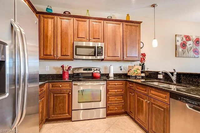 a kitchen with stainless steel appliances granite countertop a stove a sink and a refrigerator