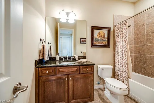 a bathroom with a granite countertop toilet sink and mirror