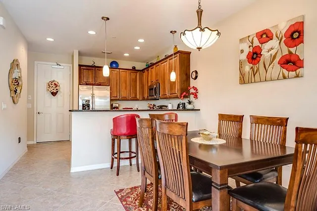 a kitchen with stainless steel appliances kitchen island granite countertop a table chairs and a refrigerator