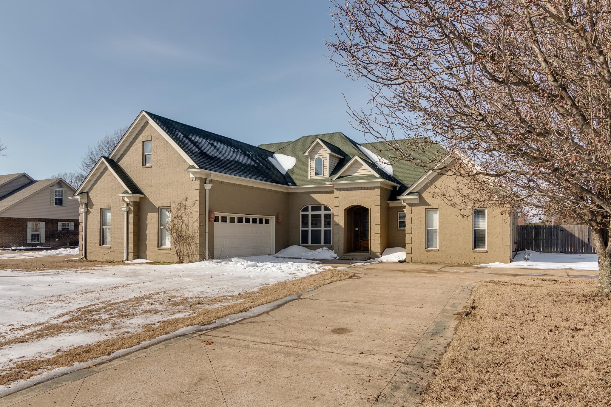 Traditional-style home featuring a shingled roof, brick siding, and an attached garage