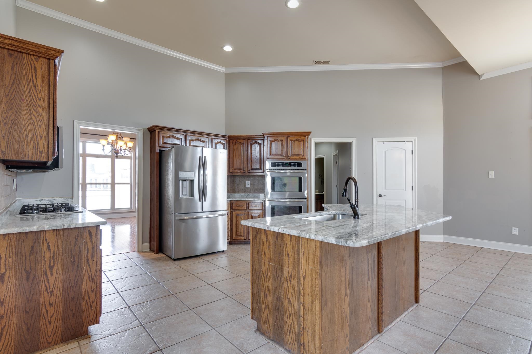 43 Tipton Rdg Cove Munford, TN 38058 - Photo 12 of 30 Kitchen with stainless steel appliances, light stone countertops, tasteful backsplash, light tile patterned floors, and ornamental molding