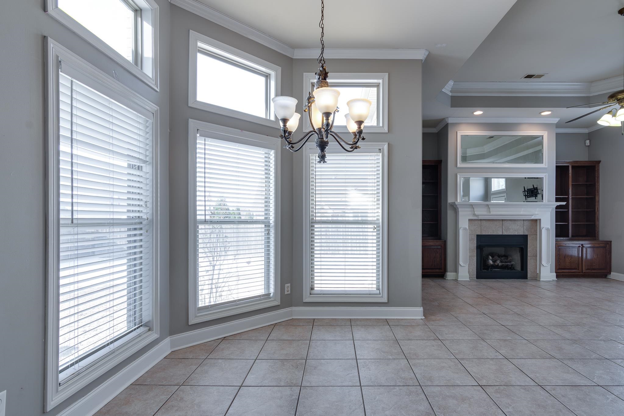 43 Tipton Rdg Cove Munford, TN 38058 - Photo 14 of 30 Unfurnished breakfast area with crown molding, a ceiling fan, healthy amount of natural light, a tile fireplace, and light tile patterned floors