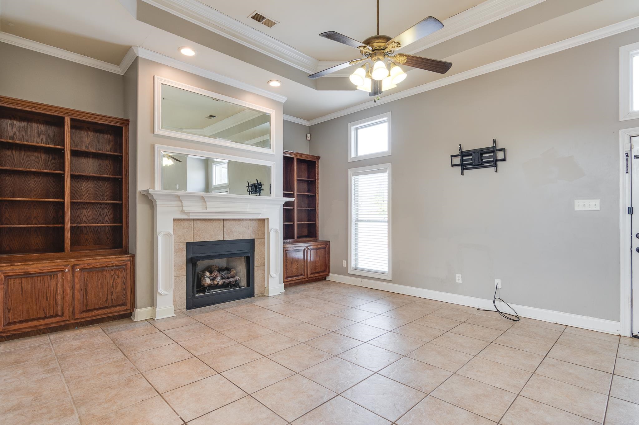43 Tipton Rdg Cove Munford, TN 38058 - Photo 15 of 30 Unfurnished hearth room featuring ceiling fan, crown molding, a fireplace, and light tile patterned floors