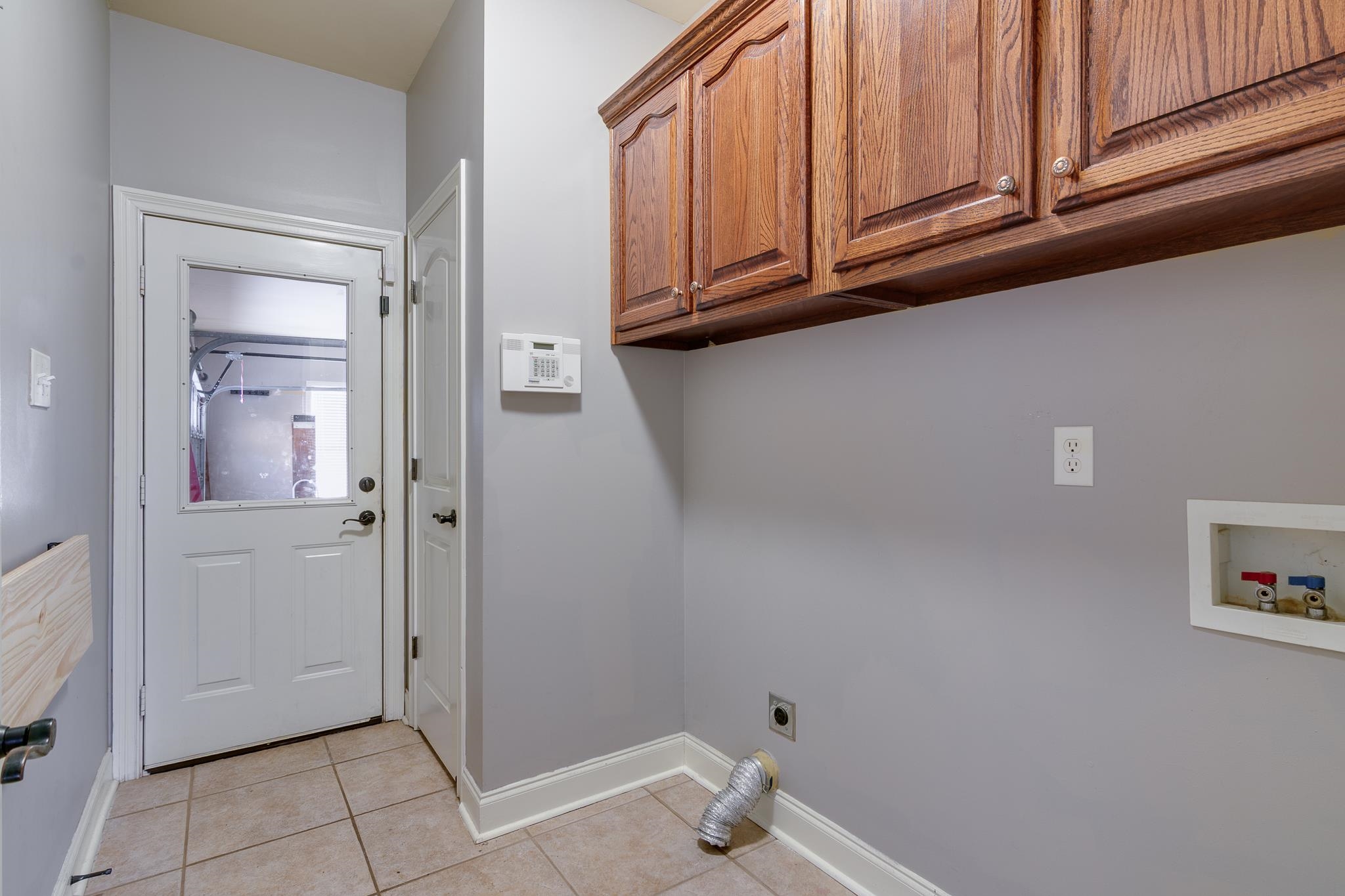 43 Tipton Rdg Cove Munford, TN 38058 - Photo 22 of 30 Laundry room featuring hookup for an electric dryer, cabinet space, washer hookup, and light tile patterned flooring