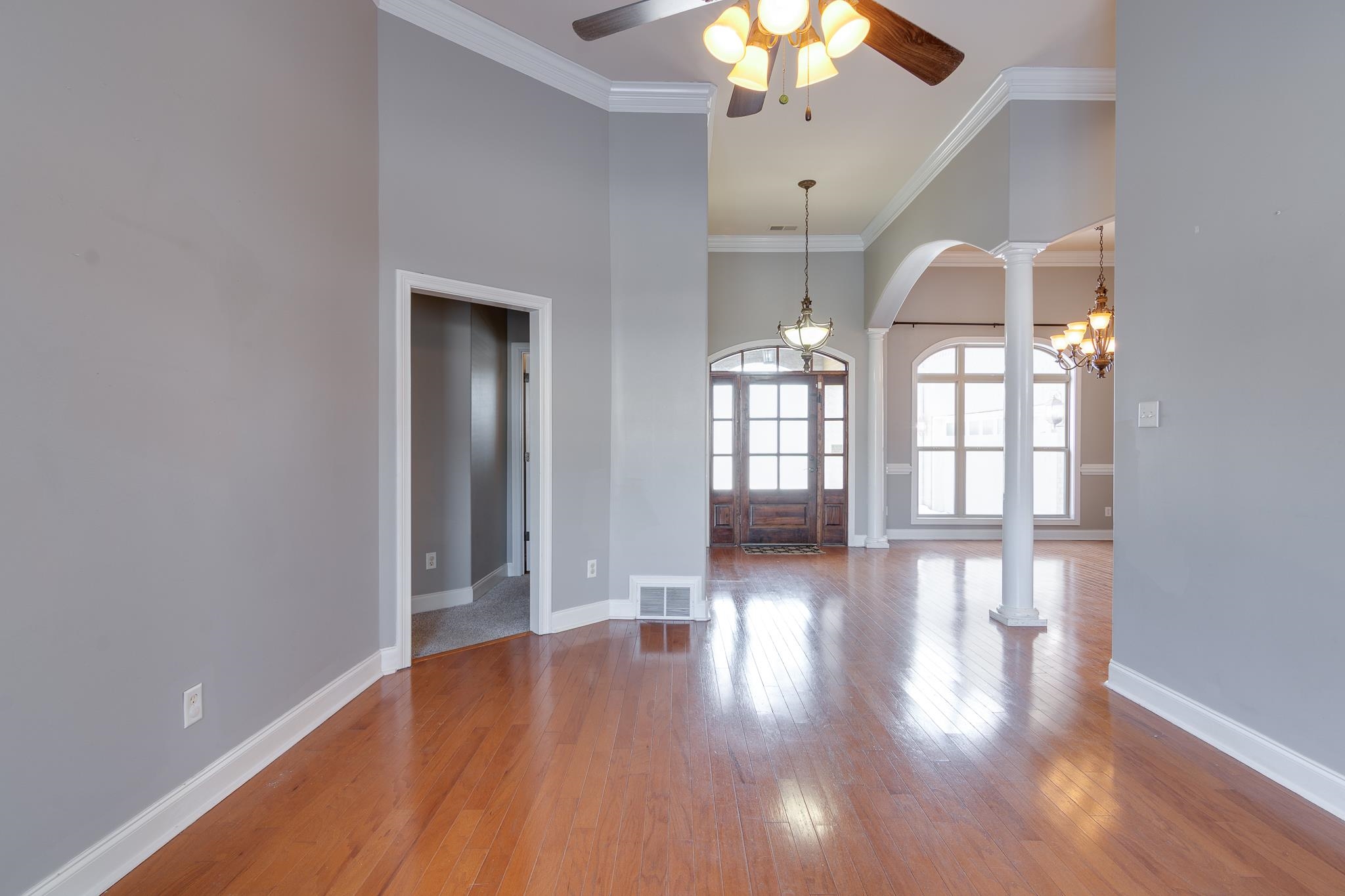 43 Tipton Rdg Cove Munford, TN 38058 - Photo 5 of 30 Unfurnished family room with ornate columns, wood-type flooring, ceiling fan, arched walkways, and ornamental molding