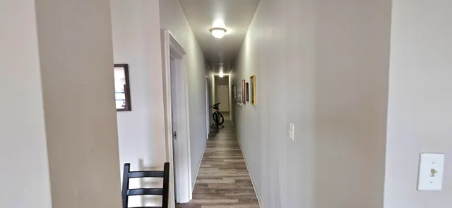 a view of a hallway with wooden floor and closet