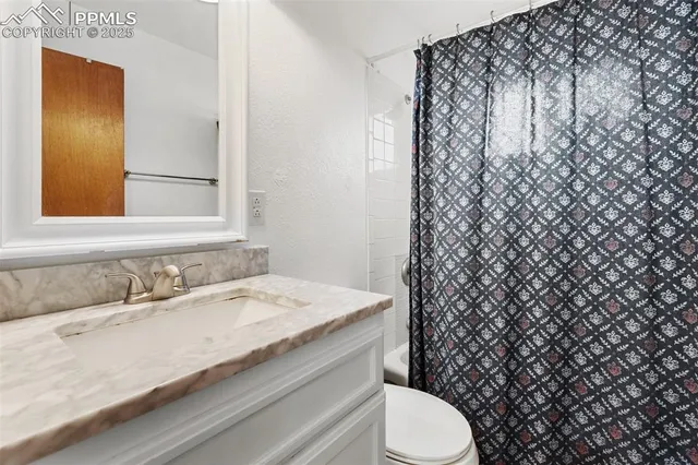 a bathroom with a granite countertop toilet and a sink