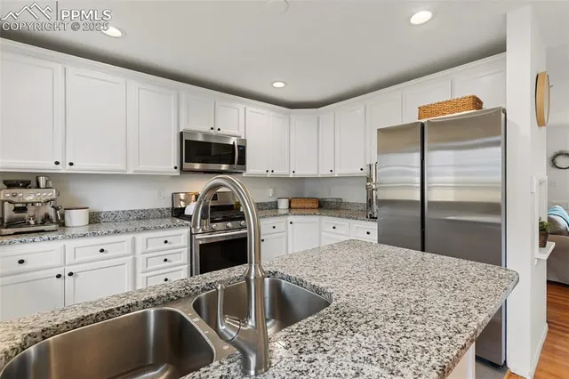 a kitchen with granite countertop a sink refrigerator and cabinets
