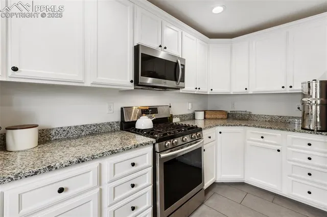 a kitchen with granite countertop white cabinets and stainless steel appliances
