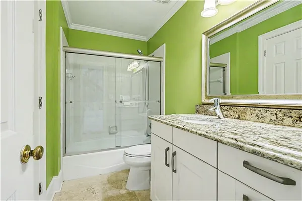 a bathroom with a granite countertop sink a toilet and shower