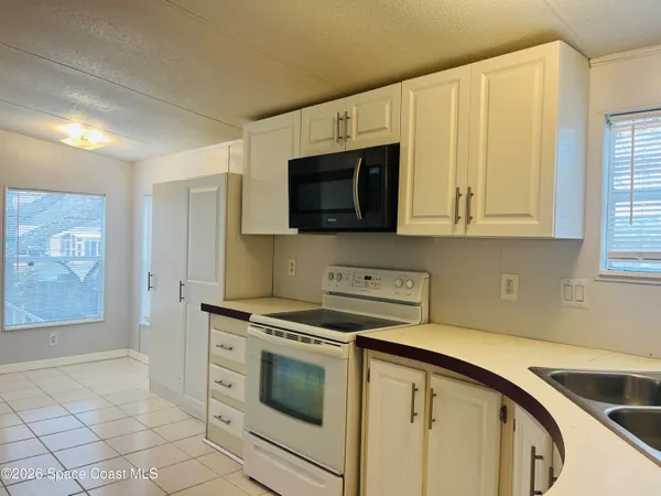a utility room with stainless steel appliances granite countertop a stove a microwave and a sink