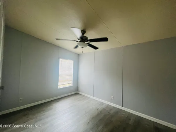 an empty room with windows and fan