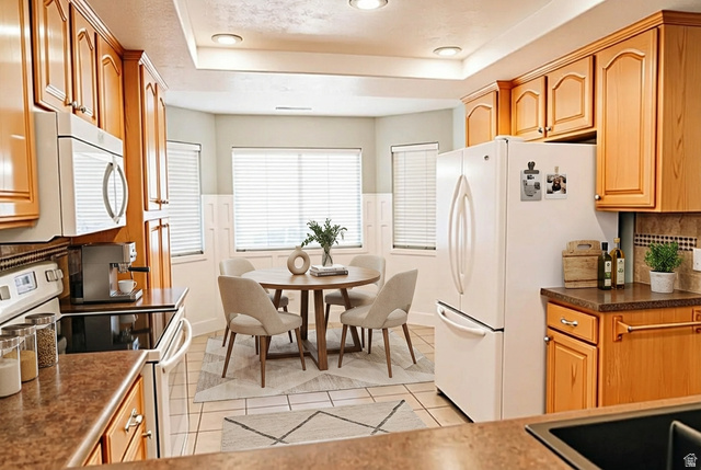 1825 West Mathis Park Place, Unit 40 St. George, UT 84770 - Photo 21 of 28 Kitchen featuring white appliances, dark countertops, tasteful backsplash, a tray ceiling, and light tile patterned flooring