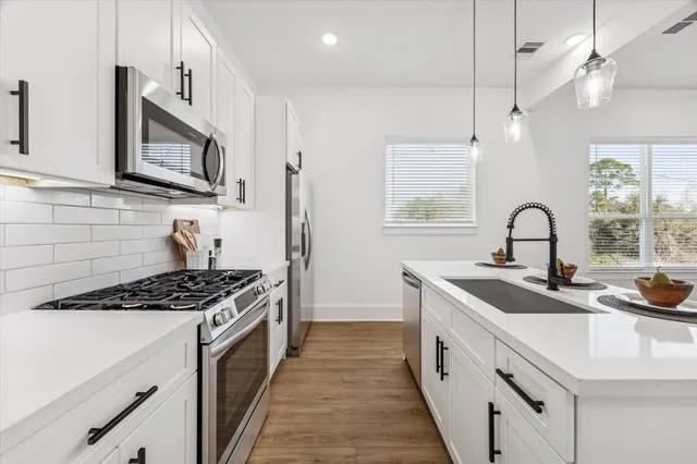 a kitchen with stainless steel appliances a sink a stove and cabinets