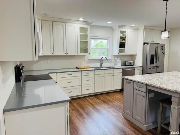 a kitchen with stainless steel appliances granite countertop wooden floors a stove a sink and a refrigerator